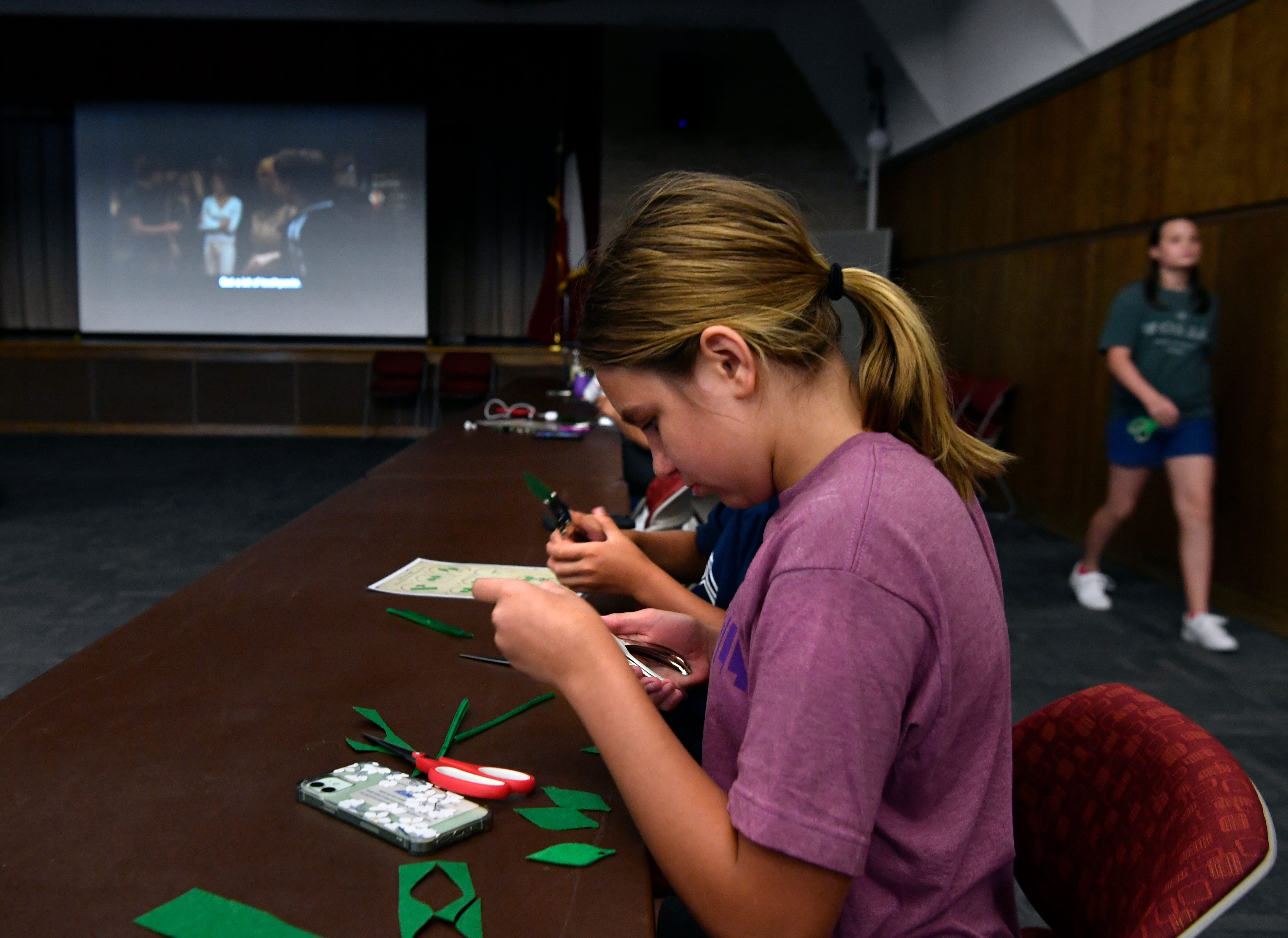Abilene Cheek, 11, works on a craft next to her brother, Jack, as a <a href='http://www.movierental.com/link/potter'>Harry Potter</a> movie plays on the auditorium screen at the Abilene Public Library's Main Branch July 14. The final movie installment, coupled with a wand-creating craft, will take place at 1:30 p.m. Wednesday.