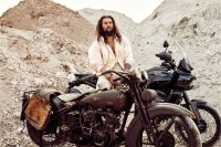 Jason Momoa standing in front of vintage Harley Davidson motorcycles with desert backdrop